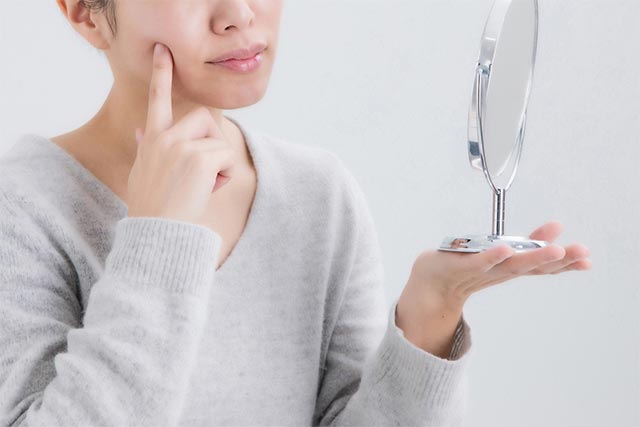 鏡で肌の状態を確認する女性